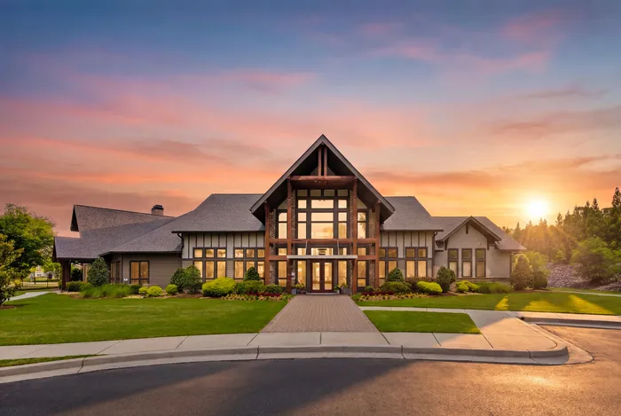 Magnificent upscale home exterior with a grand entrance, lush landscaping, and a stunning sunset backdrop.