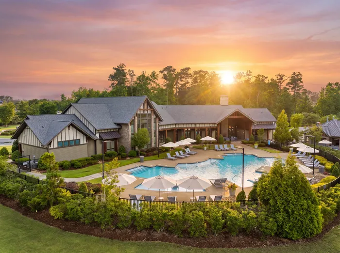 Luxurious resort-style clubhouse with a beautiful pool, surrounded by lush greenery and stunning sunset views.