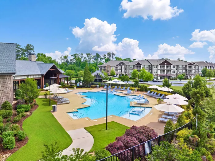 Luxurious apartment complex featuring a pristine swimming pool, lush landscaping, and stylish outdoor seating, perfect for relaxation and leisure.