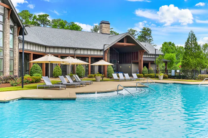 Inviting luxury apartment complex with a sparkling outdoor pool, elegant sundeck, and lush landscaping.