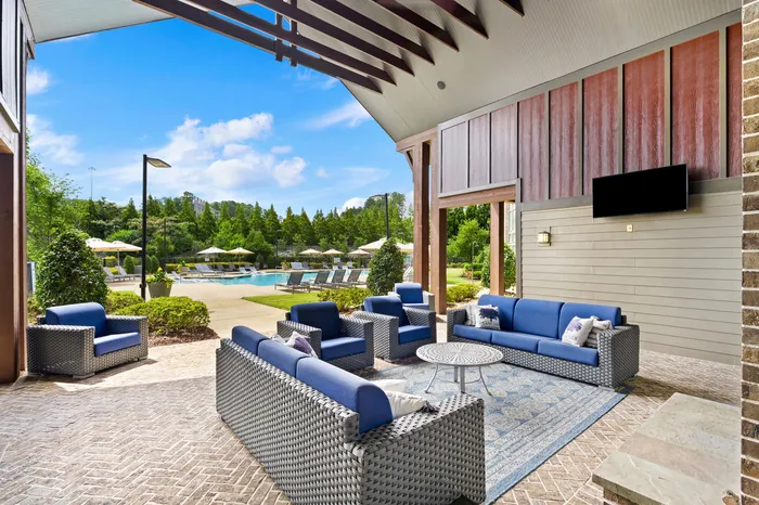 Charming outdoor lounge with elegant wicker furniture overlooking a pristine pool area bathed in natural sunlight.