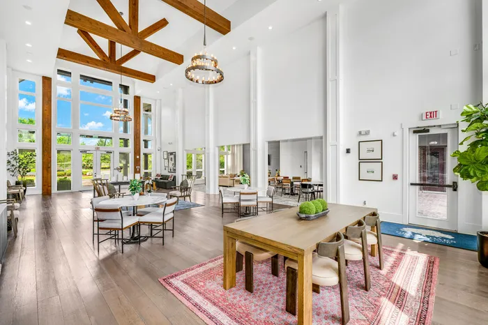 Spacious and luminous communal area with elegant wooden beams, large windows, and stylish seating arrangements perfect for social gatherings.