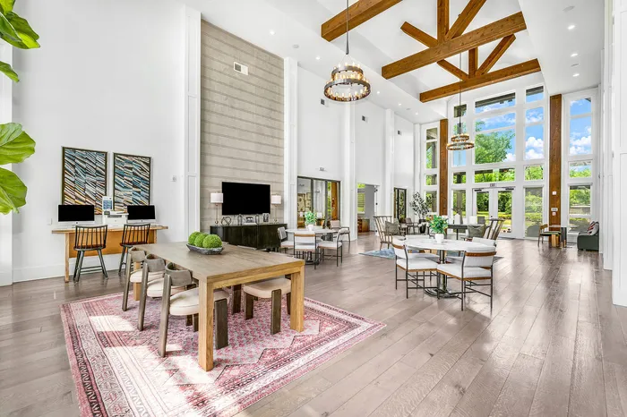 Luxurious open-concept living space featuring high ceilings, elegant wooden beams, and abundant natural lighting. Includes stylish dining and lounge areas with modern decor.
