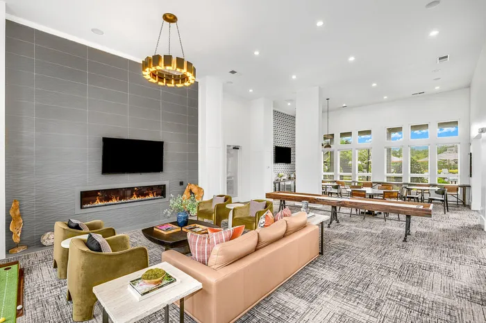 Elegant communal living space with modern furnishings, featuring a cozy fireplace, stylish pendant lighting, and bright natural light from large windows.