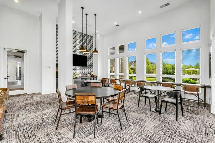 Bright and modern communal dining area with stylish furnishings, large windows offering scenic outdoor views, and sleek pendant lighting.
