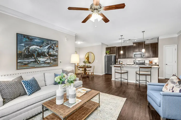 Elegant modern living room with cozy seating, artistic decor, and an open-plan kitchen featuring sleek appliances and a stylish breakfast bar.