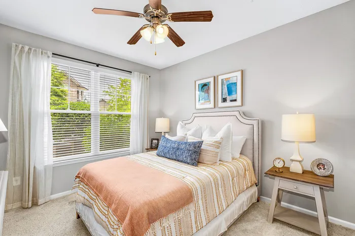 Charming bedroom with elegant decor, featuring a cozy bed, stylish nightstand, and large window offering natural light and scenic views.