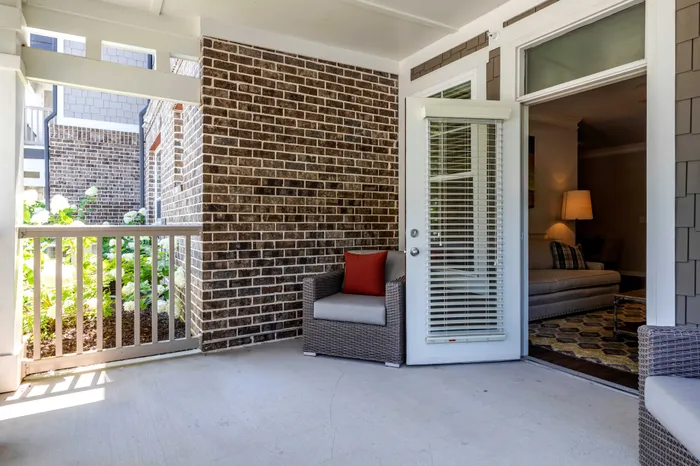 Charming patio with cozy seating, open doorway leading to a warmly lit living room, perfect for relaxation.