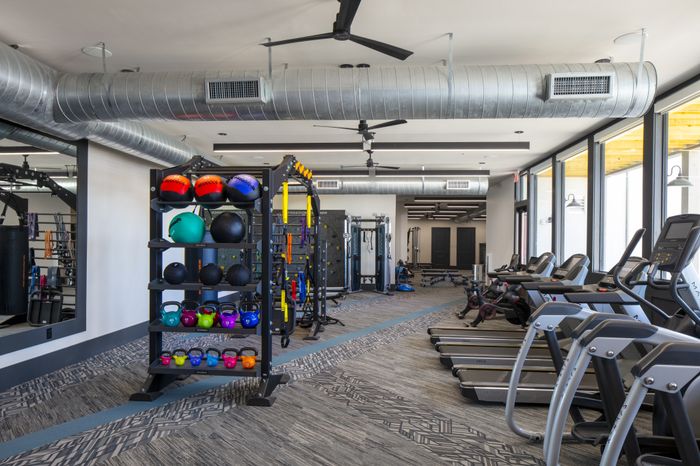 Modern fitness center with state-of-the-art equipment, sleek treadmills, vibrant kettlebells, and excellent natural lighting.