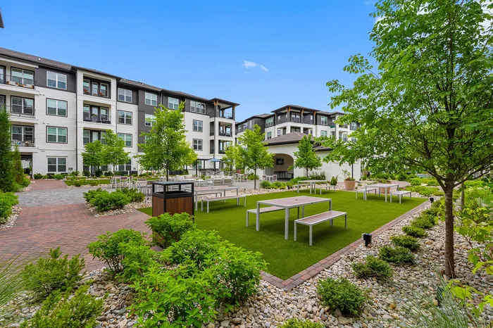 Charming apartment complex courtyard featuring lush landscaping, modern seating areas, and a serene outdoor ambiance.