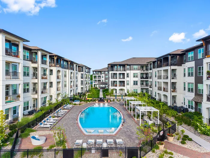 Luxurious apartment complex with elegant architecture surrounding a sparkling pool oasis, perfect for relaxation and social gatherings.