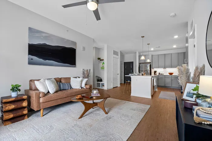 Chic living room featuring a cozy sofa, stylish coffee table, and modern open-concept kitchen with elegant lighting.