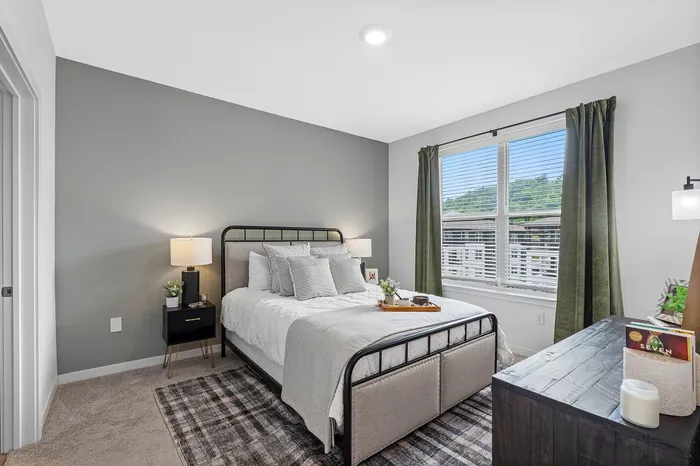 Inviting bedroom with chic decor, featuring a cozy bed with a modern metal frame, plush pillows, and elegant lighting, complemented by large window views.