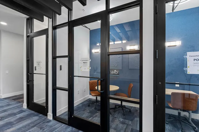 Modern coworking pods with sleek glass doors and comfortable seating, offering a stylish and productive workspace environment.