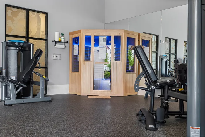 Modern gym space with advanced exercise equipment and a stylish sauna, perfect for wellness and fitness.
