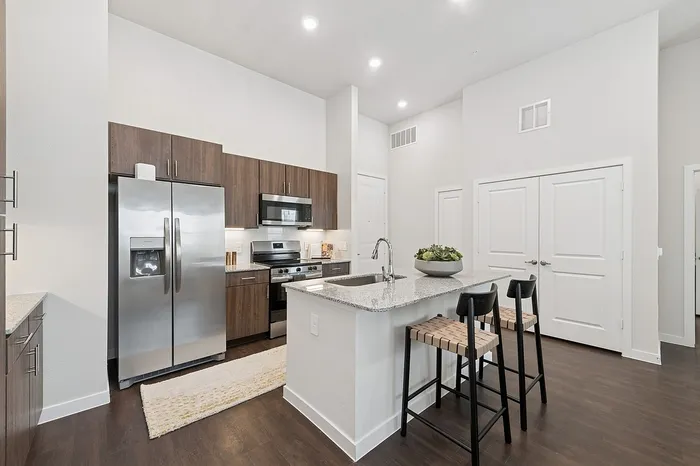 Contemporary kitchen with sleek stainless steel appliances, elegant dark wood cabinets, and a stylish breakfast bar perfect for modern living.
