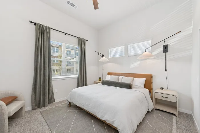 Bright and inviting bedroom with a modern bed, elegant lighting, and large window offering natural light.