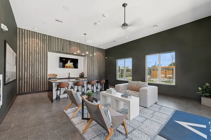 Chic and modern lounge area featuring a cozy seating arrangement, stylish wooden chairs, and a sleek bar with leather stools against a trendy paneled wall.