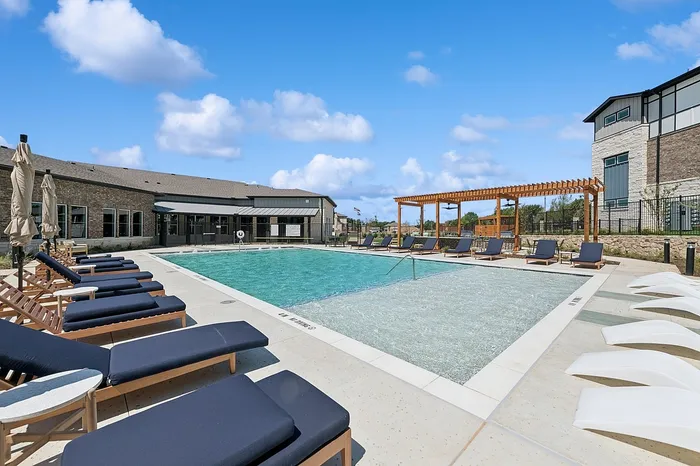 Luxurious outdoor pool area with stylish lounge chairs and a pergola, perfect for relaxation and soaking up the sunshine.