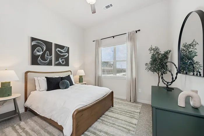 Chic bedroom featuring a cozy bed with elegant decor, natural light from a large window, and modern artwork on the wall.