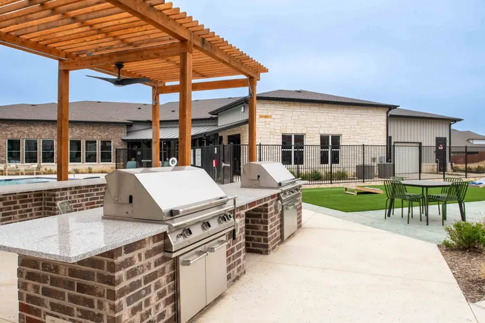 Modern outdoor barbecue area with sleek stainless steel grills and inviting seating, perfect for entertaining and relaxing by the pool.