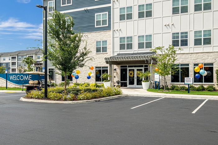 Inviting apartment entrance with vibrant balloons and lush landscaping, welcoming future residents with style and comfort.
