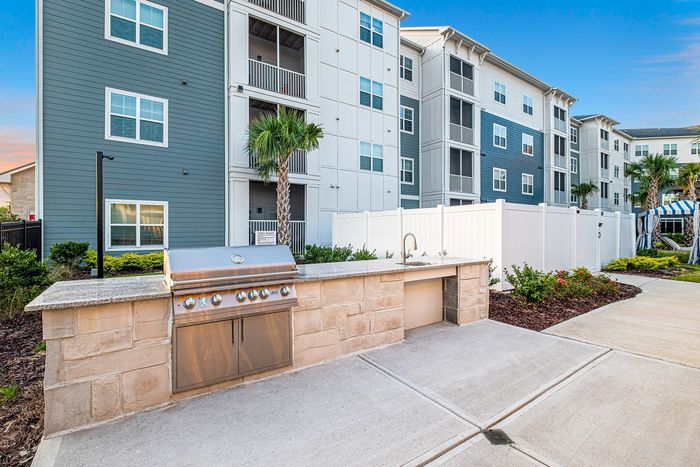 Contemporary apartment complex with charming outdoor BBQ area and lush landscaping.