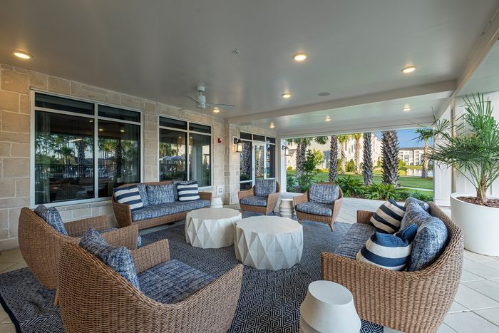 Elegant outdoor lounge with wicker furniture and stylish decor, set in a charming garden view setting.