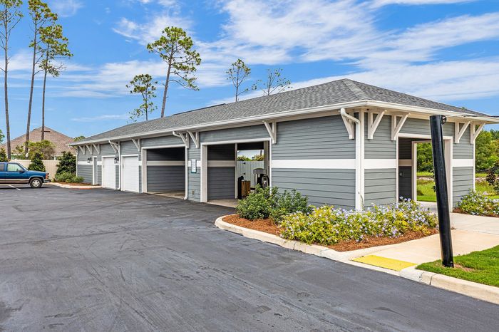 Charming community garage in a well-maintained area with beautiful landscaping and clear blue skies.
