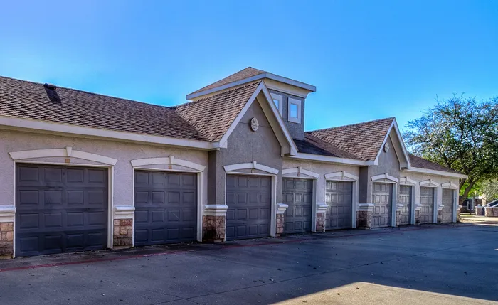 Elegant row of attached garages with stylish architectural details and sunlit surroundings, perfect for premium apartment living.
