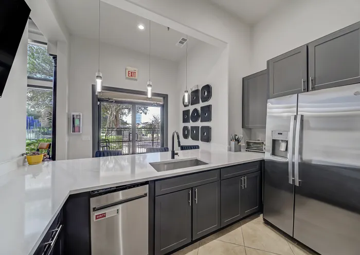 Modern kitchen with sleek stainless steel appliances, dark cabinetry, and a spacious white quartz countertop, offering a stylish and functional space for cooking.