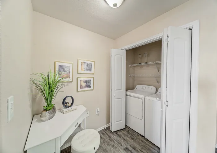 Charming laundry nook with modern washer and dryer, complemented by sleek white cabinetry and tasteful decor.