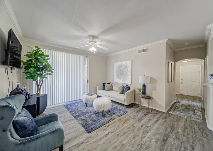 Elegant living room with modern decor, featuring a plush sofa, accent chairs, stylish artwork, and large windows allowing natural light to flow through.