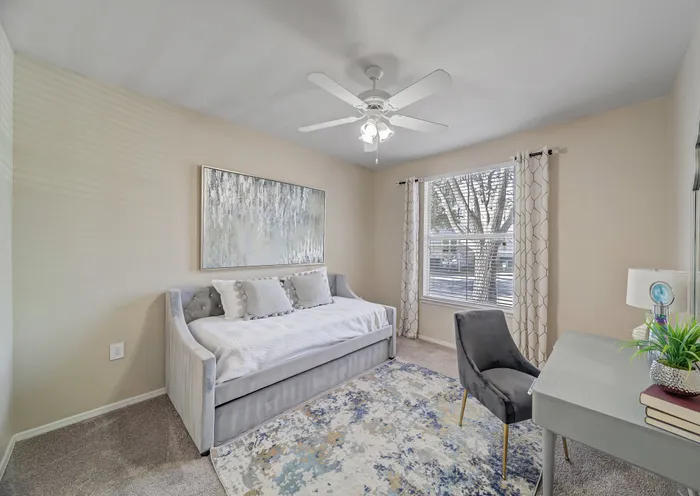 Bright and cozy bedroom with elegant decor, featuring a plush daybed, stylish artwork, and a spacious window overlooking nature.