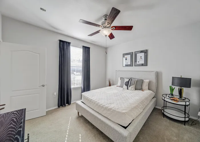 Bright, cozy bedroom with a stylish ceiling fan, natural light, and elegant decor.