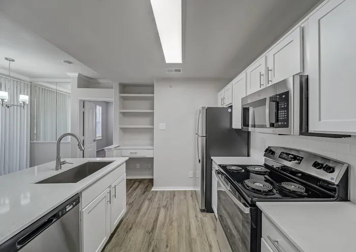 Modern kitchen with sleek white cabinetry, stainless steel appliances, and elegant light fixtures, creating a bright and inviting space.