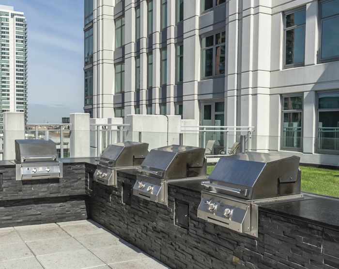 Chic urban rooftop with modern stainless steel grills against a backdrop of sleek high-rise buildings, perfect for entertaining.