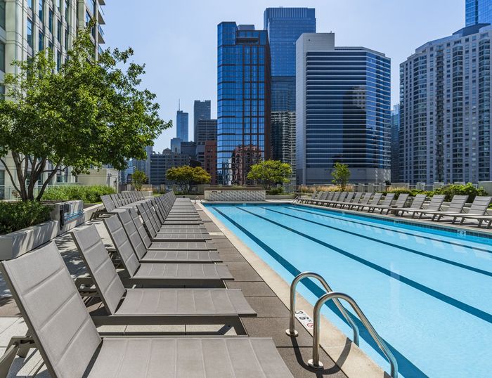 Luxurious rooftop pool with modern loungers overlooking stunning city skyline, perfect for relaxation and leisure.