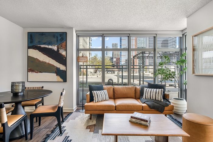 Modern living room with a stylish leather sofa, sleek coffee table, and large windows offering a stunning cityscape view, featuring contemporary art and chic decor.
