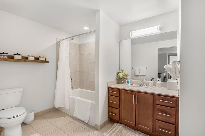 Elegant bathroom with modern fixtures, featuring a sleek vanity, bathtub with tiled surround, and ambient lighting.