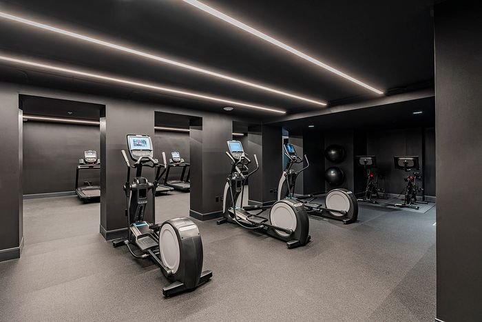 Modern fitness center with cardio machines, exercise bikes, and sleek black decor, offering a stylish workout environment.
