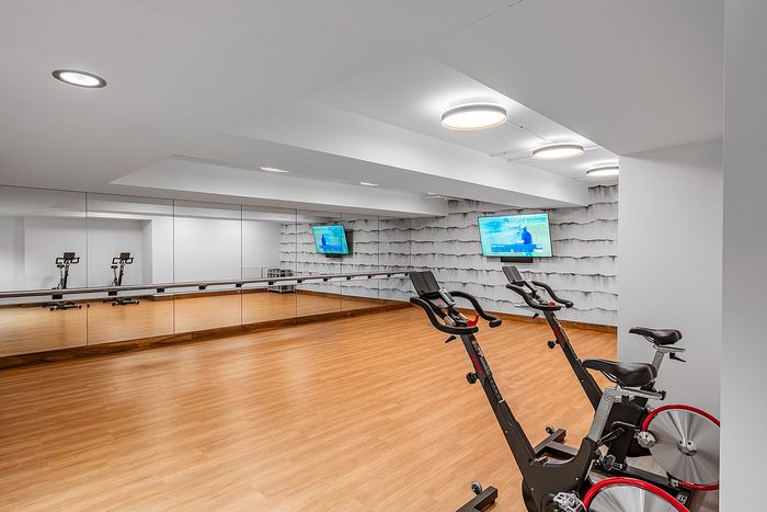 Modern apartment gym with sleek exercise bikes, mirrored walls, and bright design for an energizing workout experience.