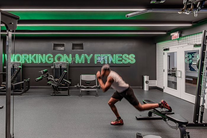 Dynamic modern gym with sleek equipment and vibrant neon sign reading 'Working On My Fitness,' perfect for an energetic workout.