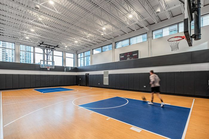 Modern indoor basketball court with sleek design, featuring high ceilings and polished wood floors, offering a premium sports experience.