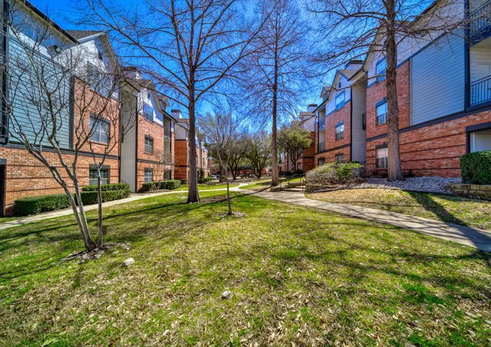 Beautiful apartment complex surrounded by lush green lawns and tall trees, offering a serene and inviting environment.