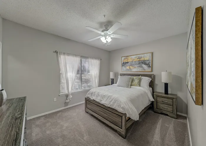 Serene bedroom with elegant decor, featuring a plush double bed, stylish lamps, and natural light filtering through sheer curtains.