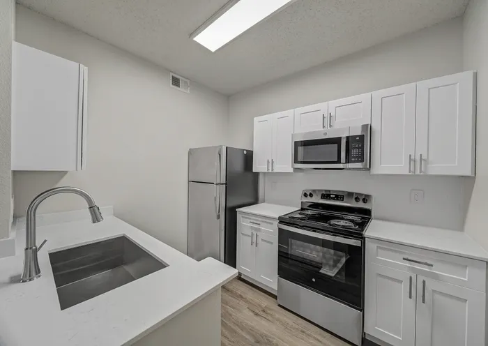 Modern kitchen with sleek stainless steel appliances, crisp white cabinetry, and elegant countertops.