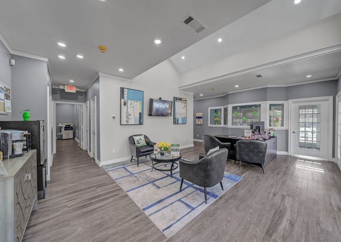 Elegant apartment lobby featuring stylish seating, modern artwork, and warm lighting on sleek wooden flooring.