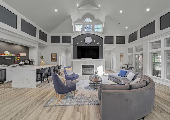 Elegant open-concept living room with vaulted ceilings, cozy seating, stylish fireplace, and modern kitchen area.