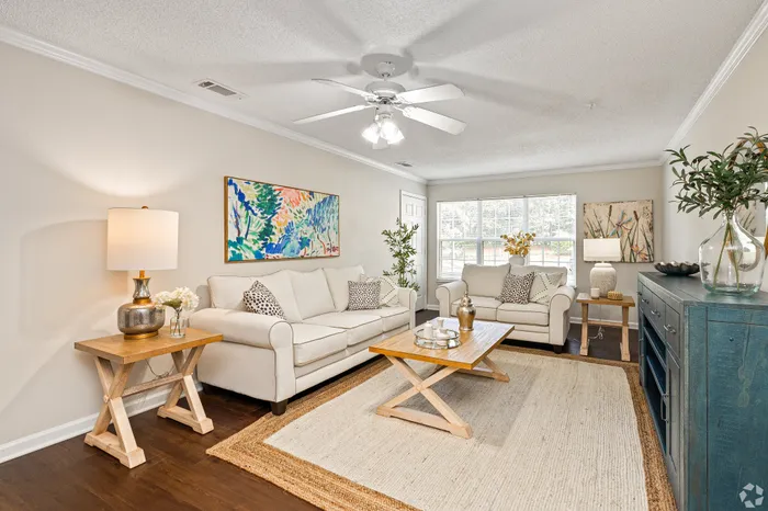 Bright and inviting living room with elegant white sofas, chic wooden tables, and vibrant artwork, perfect for relaxation and entertaining.
